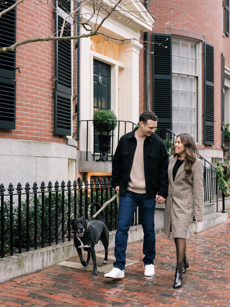 Couple walk together with their dog on a Beacon Hill street during engagement photos