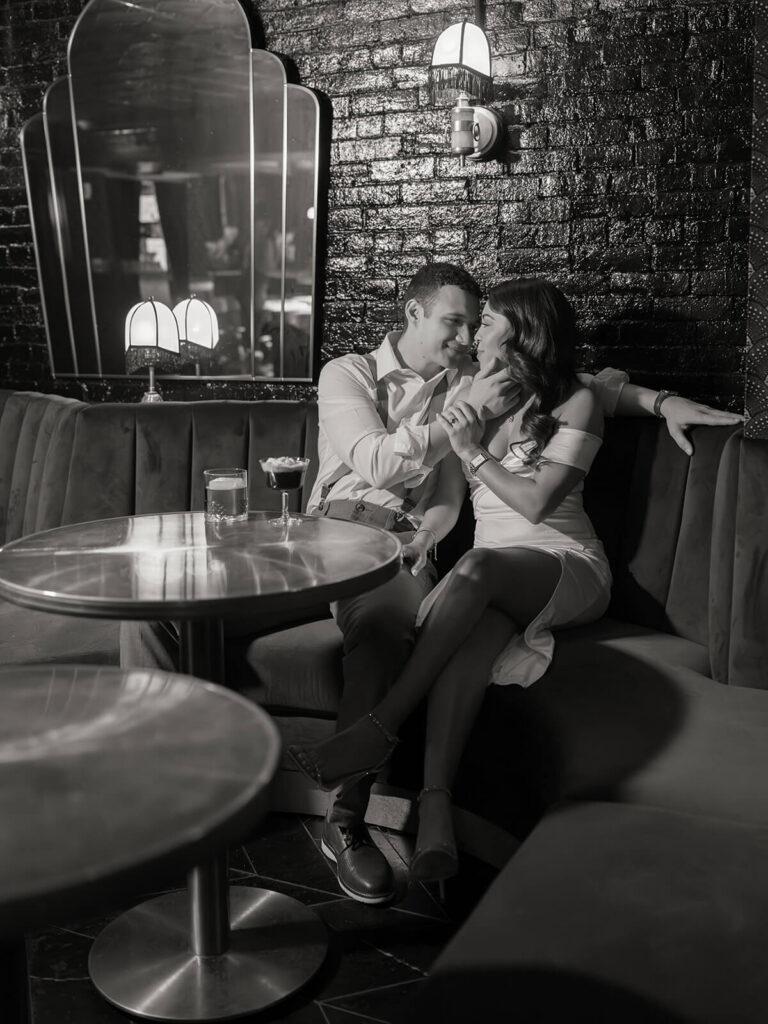 Couple sitting in a booth cuddling during Boston engagement photos in Beacon Hill at 89 Charles