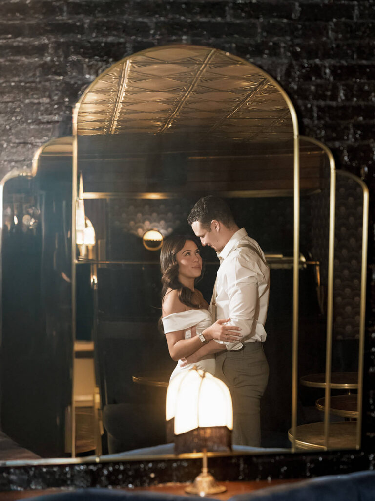 Romantic engagement portrait at 89 Charles bar in Boston Beacon Hill through mirror reflection.