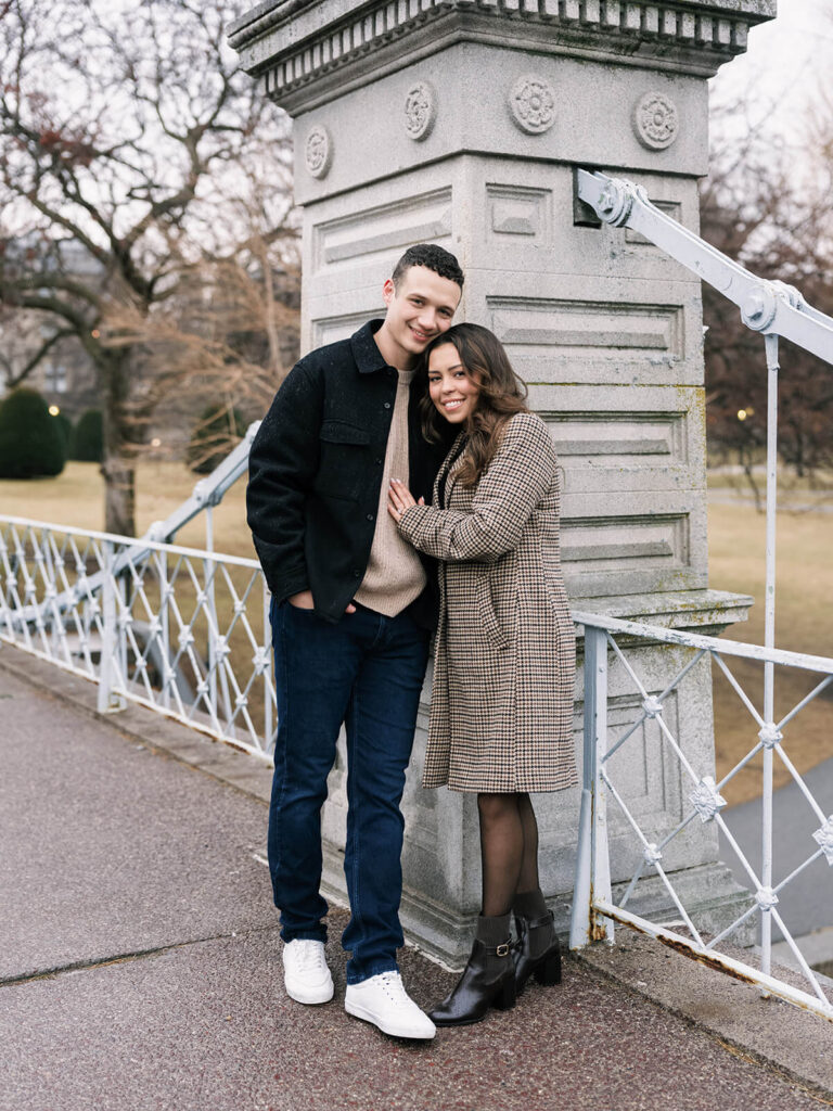 Couple stands at a pedestrian bridge entrance on the grounds of Boston Public Garden