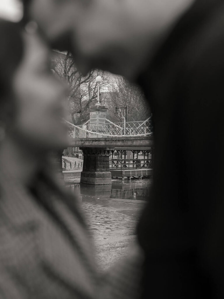 Couple stand out of focus facing each other with the pedestrian bridge in sharp focus behind them