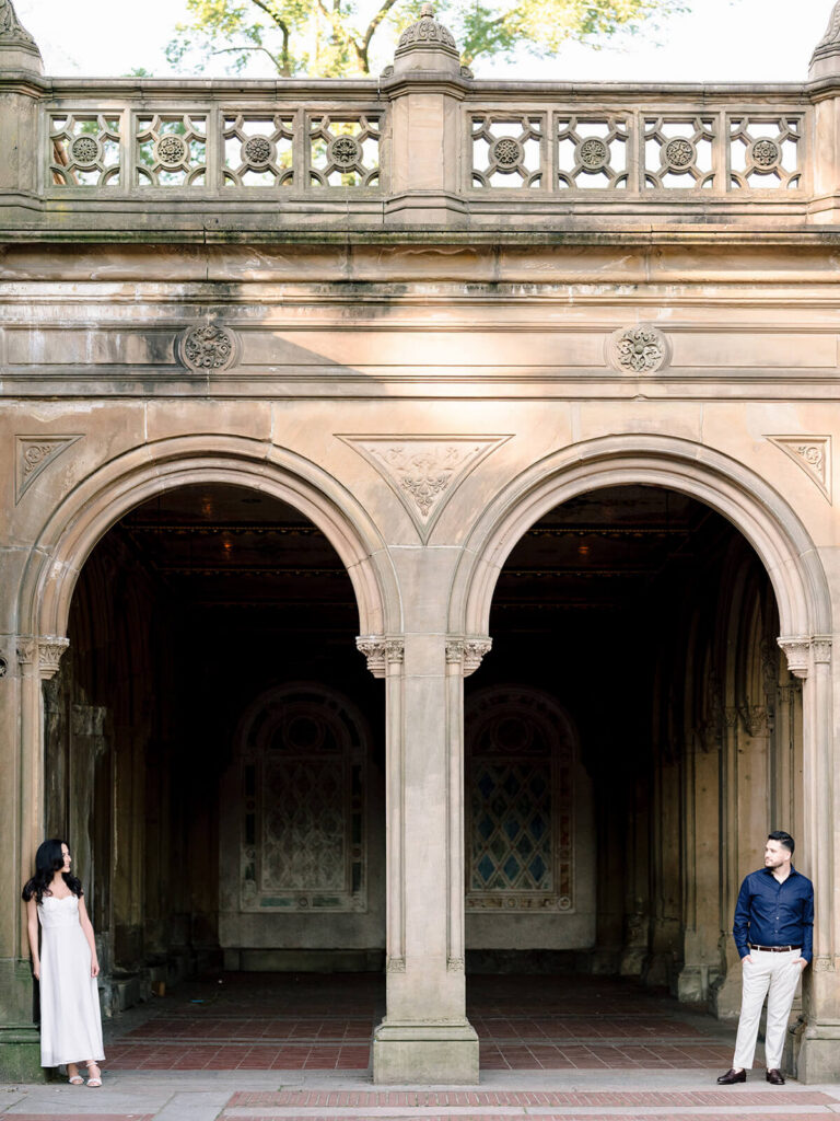 Symmetrical engagement portrait at Bethesda Terrace arcade arches Central Park NYC