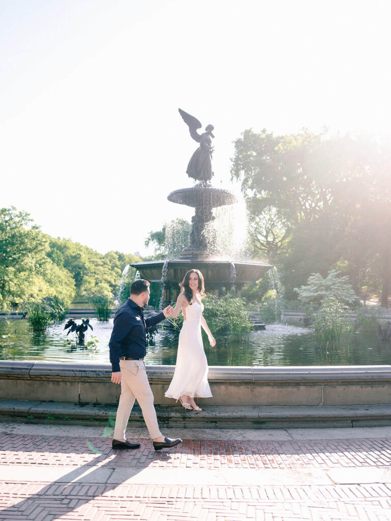 Engaged couple on Bethesda Terrace grand staircase during golden hour NYC