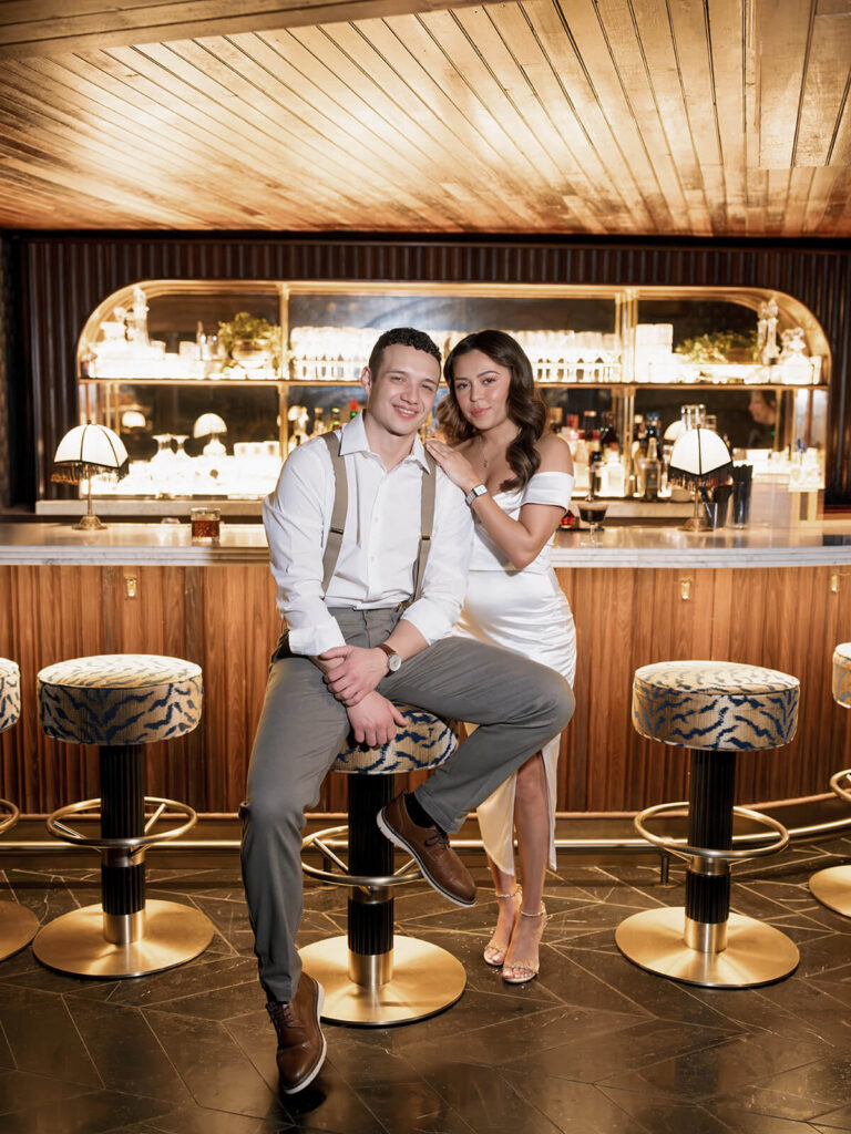 Couple posing on bar stools at mid-century cocktail bar during Boston engagement session