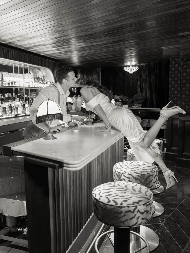 Black and white photo of couple kissing across bar counter during Boston engagement session