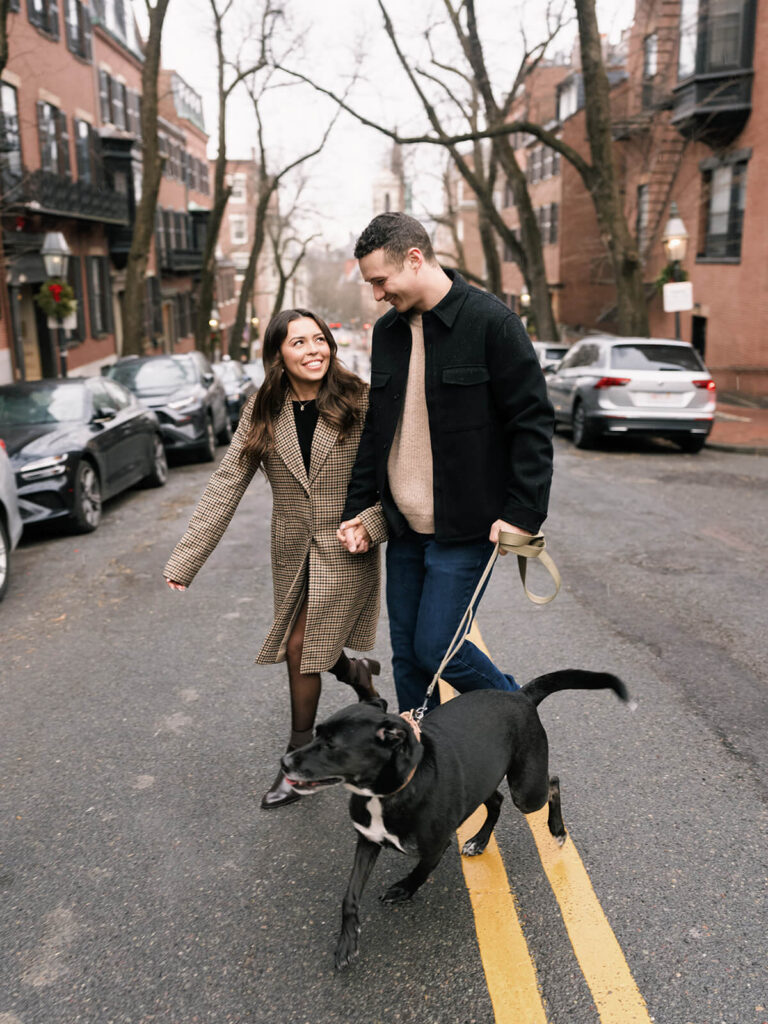 Couple walking their black dog down tree-lined Beacon Hill street on a winter day