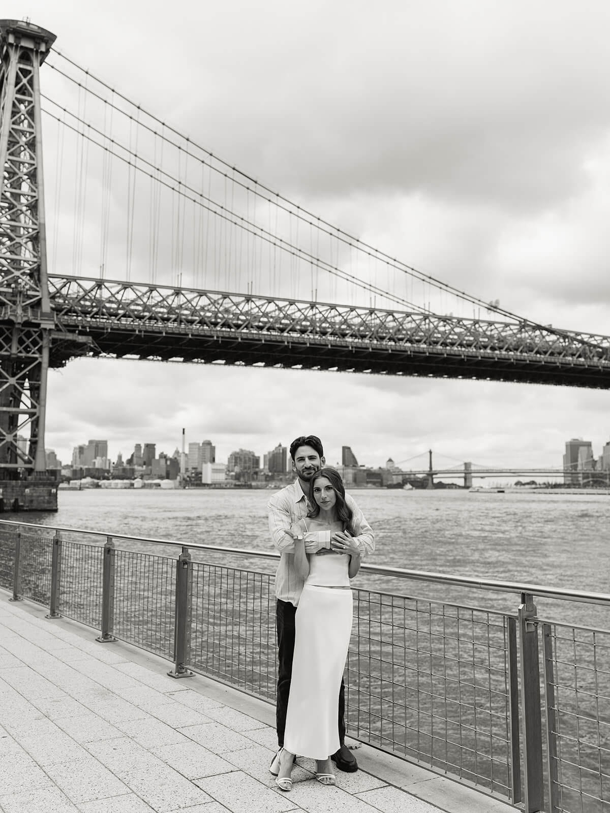 Engaged couple celebrating with waterfront NYC skyline engagement photography