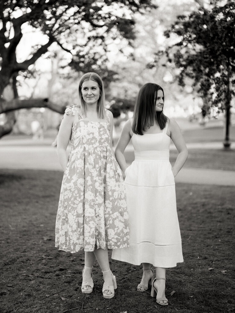 Two brides laughing together on park bench with tulip garden South End Boston