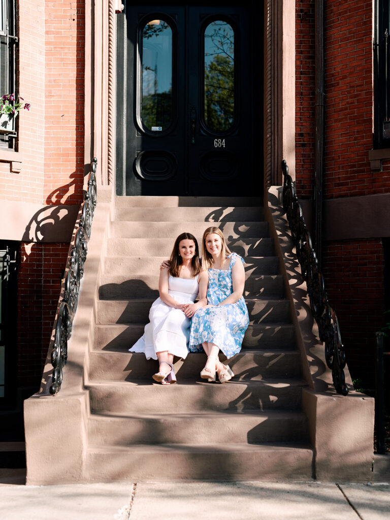 Two brides embracing by lagoon in Boston Public Garden spring engagement session