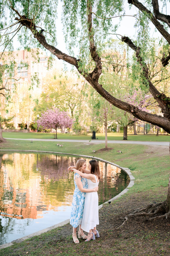 Boston engagement photos at Public Garden lagoon with flowering trees and greenery