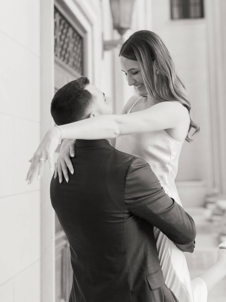 Black and white of man lifting woman in embrace classical building backdrop Gandhi Park Charlotte