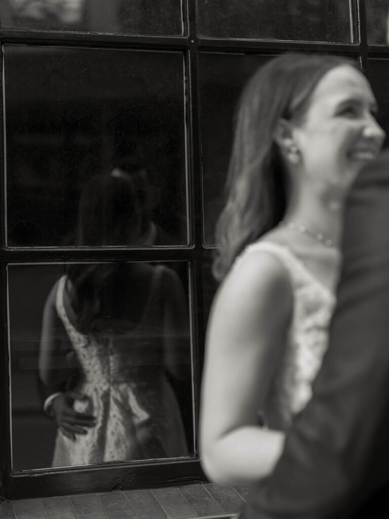 Black and white artistic shot of woman smiling with reflection in window pane Charlotte engagement