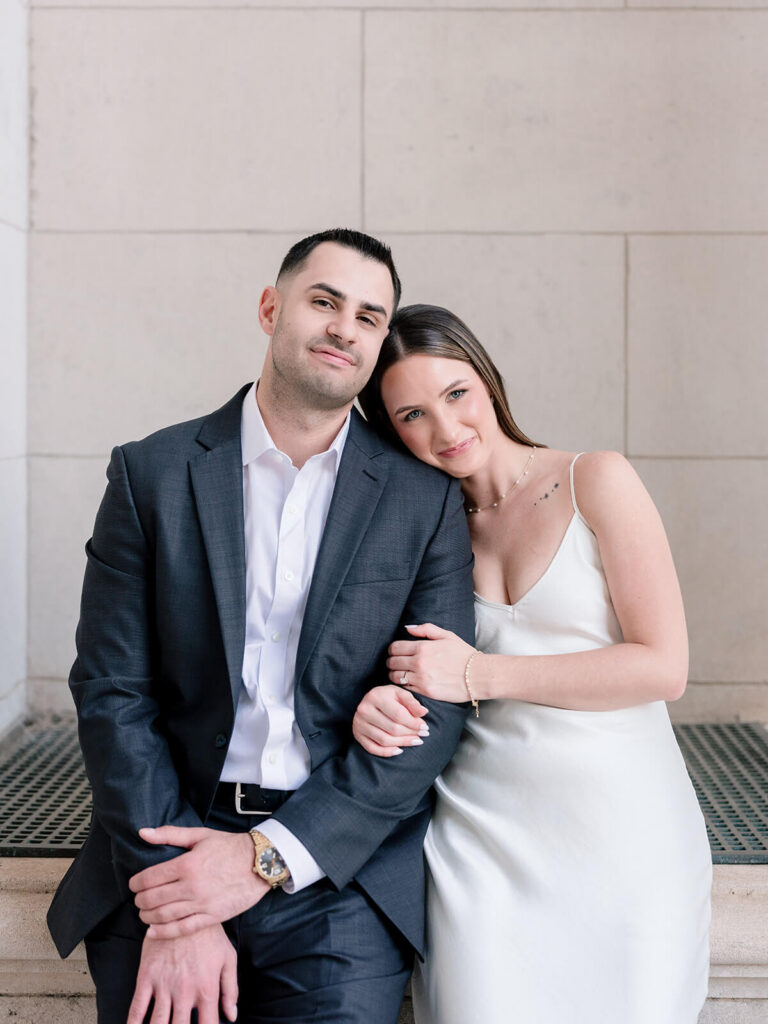 Couple posing together seated against stone wall Gandhi Park Charlotte engagement session