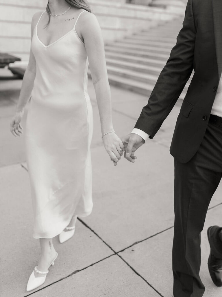 Black and white close-up of couple holding hands walking woman in white dress Gandhi Park Charlotte
