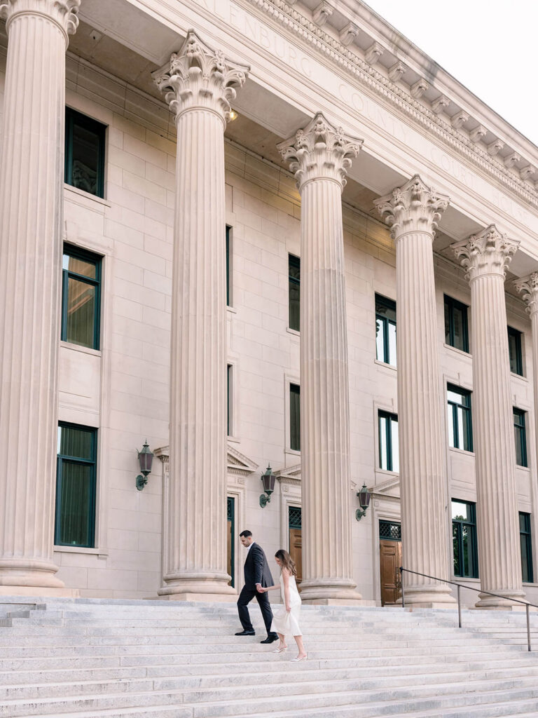 Couple descending grand stone steps of columned courthouse building Gandhi Park Charlotte