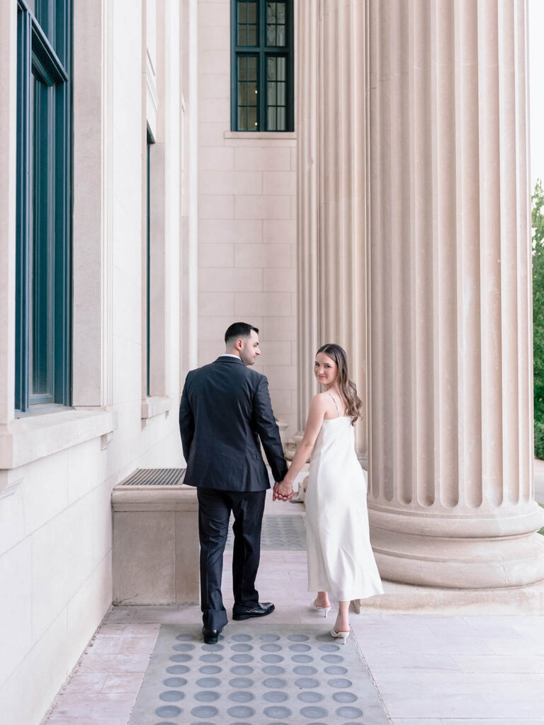 Couple holding hands near column woman looks over shoulder at camera Gandhi Park Charlotte