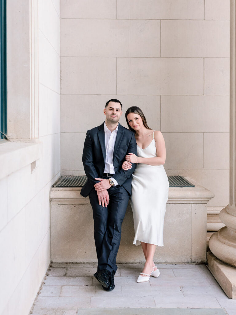 Couple leaning against stone ledge between columns Gandhi Park Charlotte engagement photos