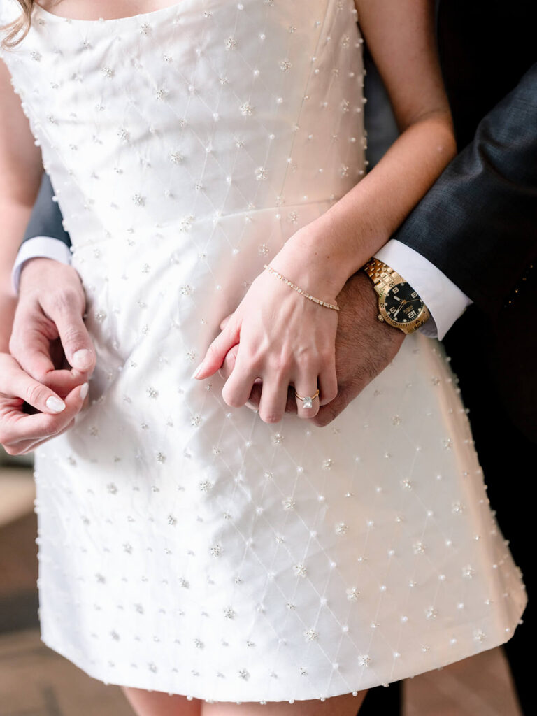 Close-up of couple's hands showing engagement ring and beaded white dress detail Charlotte engagement