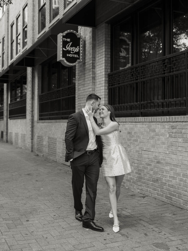 Couple laughing outside The Iveys Hotel she touches his face Charlotte engagement session