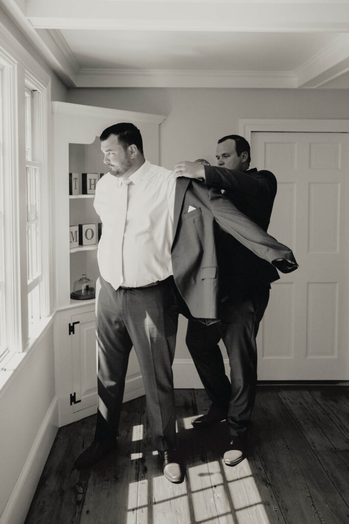 Groom getting into his jacket before the wedding in Chatham, Massachusetts