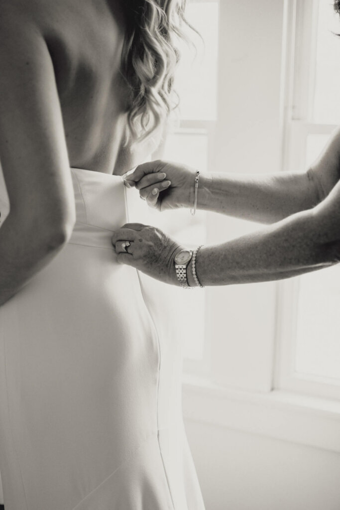 Hands fastening the back of the bride’s gown before the ceremony at Chatham Bars Inn