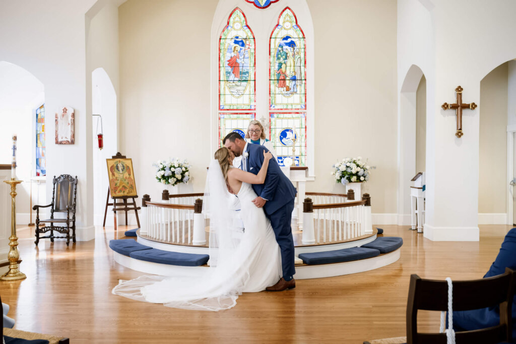 Bride and groom kissing at the altar during their Chatham church wedding ceremony