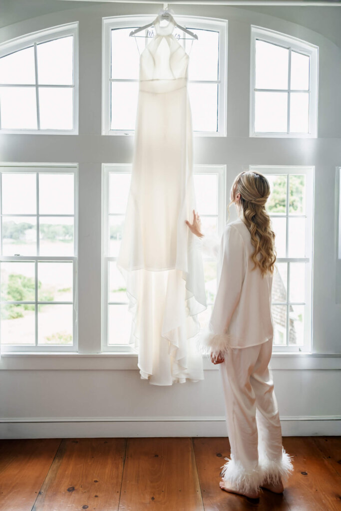 Bride standing by the window with her wedding dress before her Chatham Bars Inn wedding on Cape Cod