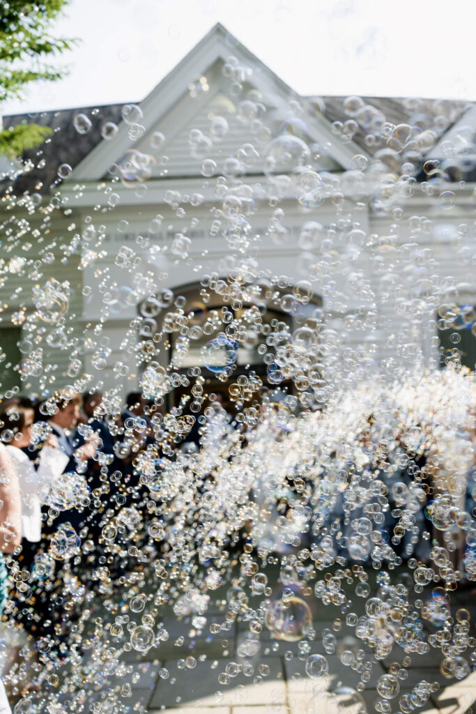 Newlyweds walking through flower petals outside the church in Chatham, Massachusetts