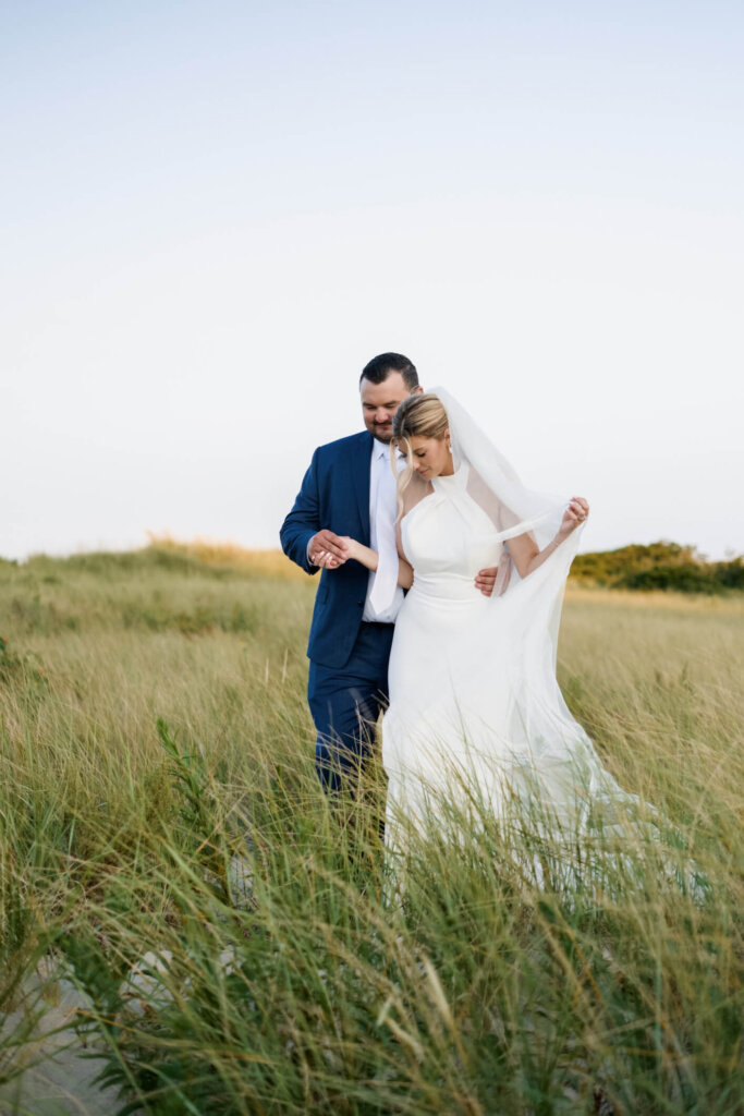 Bride and groom walking together through the dunes at Chatham Bars Inn on Cape Cod