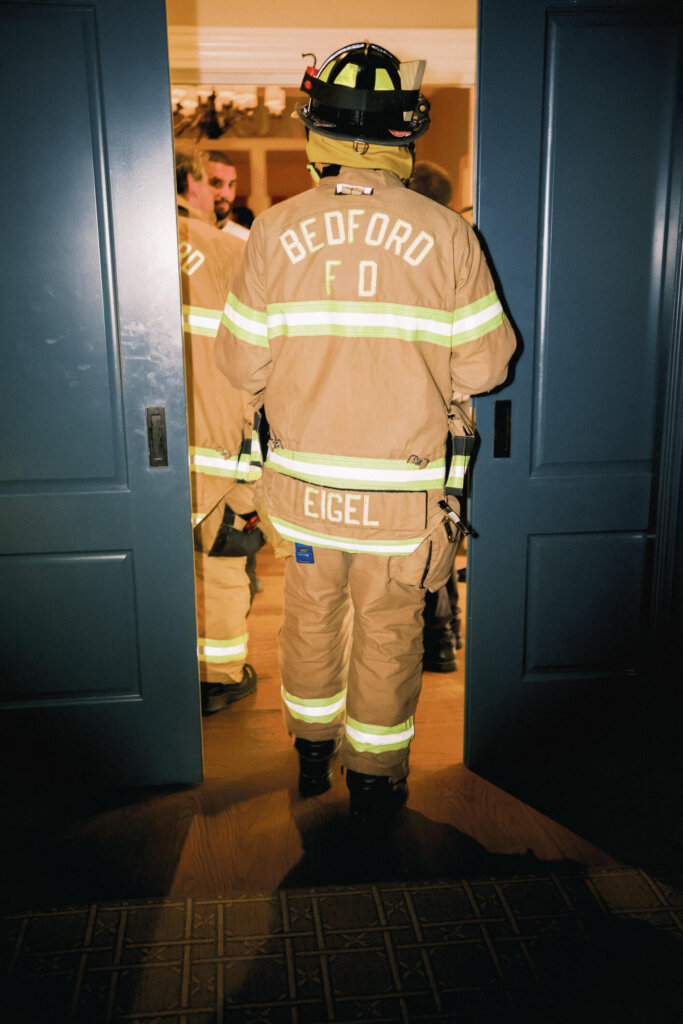 Bride wearing a firefighter jacket during the after party at Bedford Golf and Tennis Club