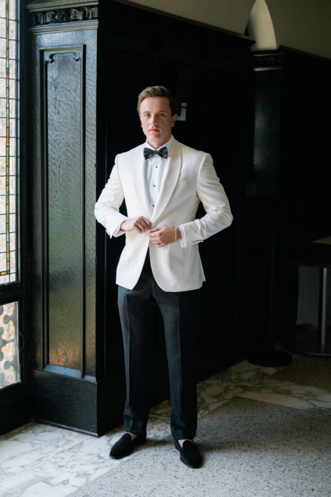Groom tying his bow tie before the Bedford Golf and Tennis Club wedding
