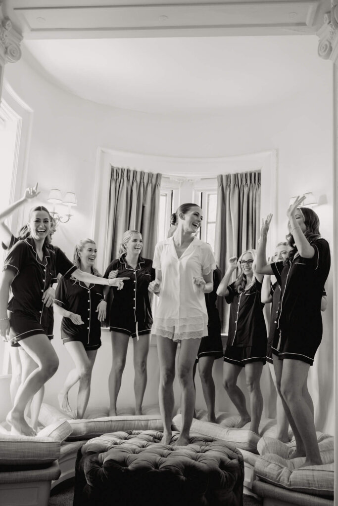 Bride in pajamas holding champagne during getting ready before her Bedford wedding
