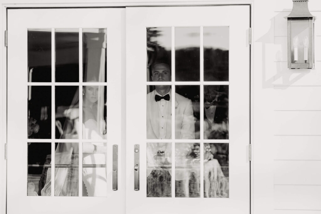 Bride and groom seen through the doors before their Bedford Golf and Tennis Club ceremony