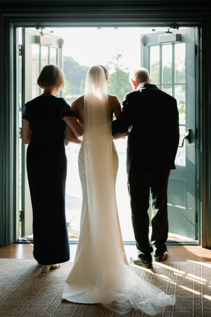 Bride entering the ceremony with her parents at Bedford Golf and Tennis Club