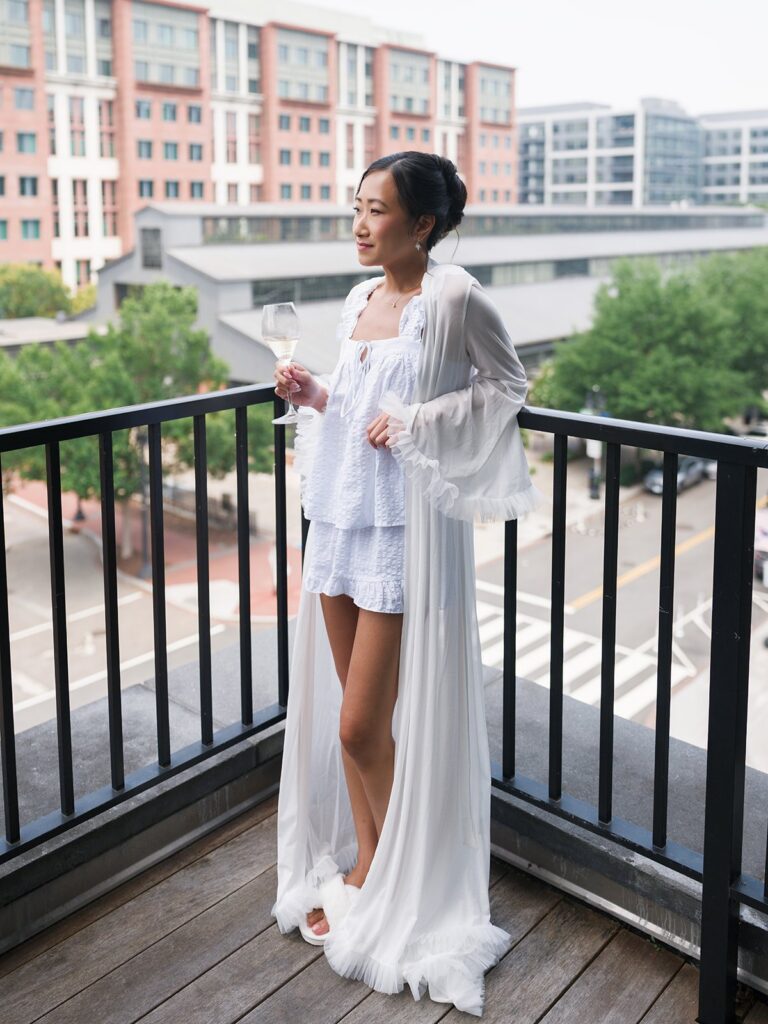 Tiffany holding a champagne glass on a Navy Yard hotel balcony before her wedding