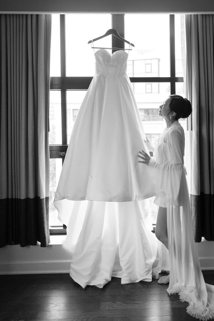 Tiffany looking at her wedding dress hanging in the hotel window