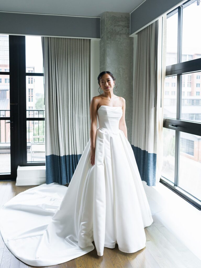 Tiffany standing by the hotel windows in her structured wedding gown