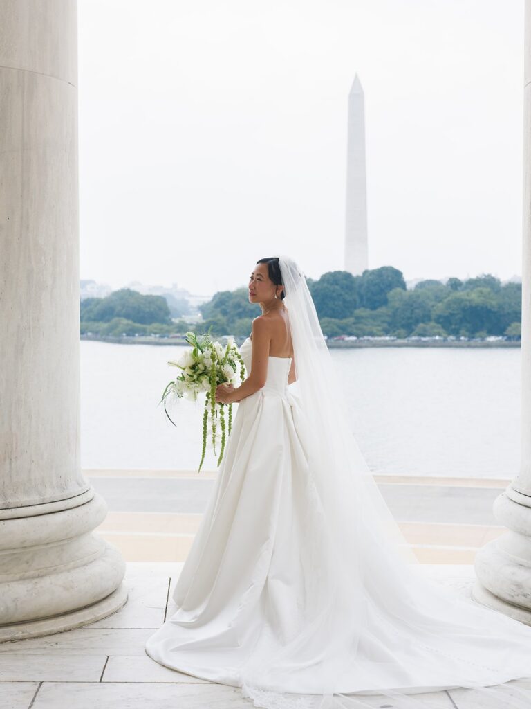 Tiffany standing between the Jefferson Memorial columns with her wedding bouquet