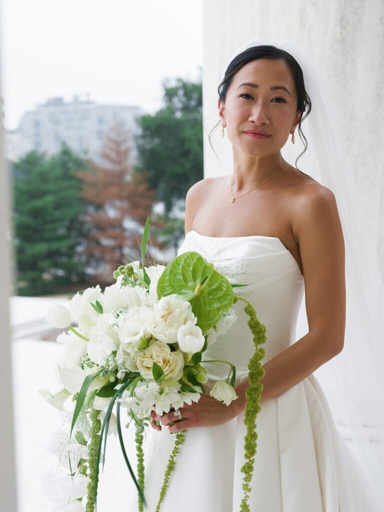 Tiffany holding a cascading green-and-white wedding bouquet at the Jefferson Memorial