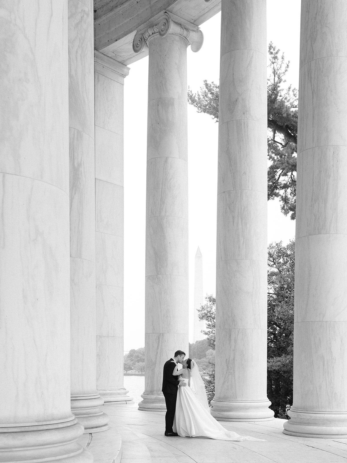 Tiffany and Tim kissing between the Jefferson Memorial columns in black and white
