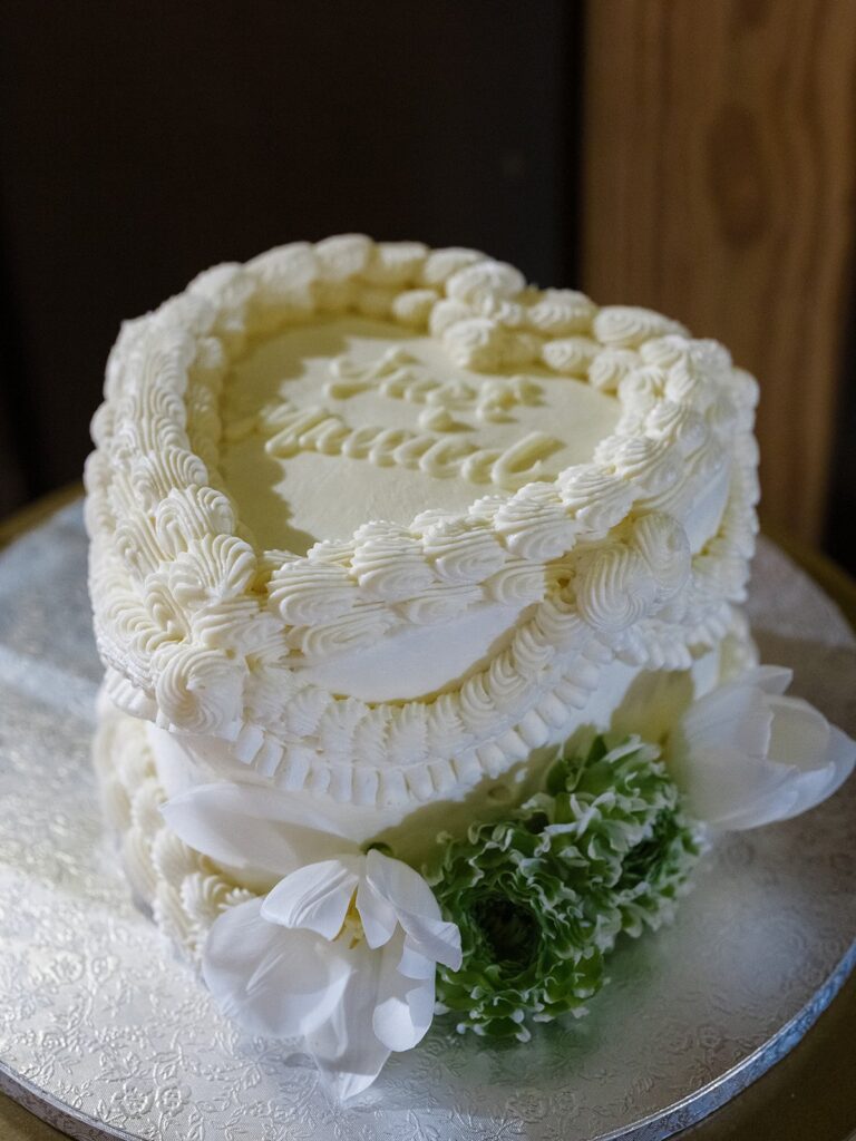 Small white wedding cake with piped details and white flowers