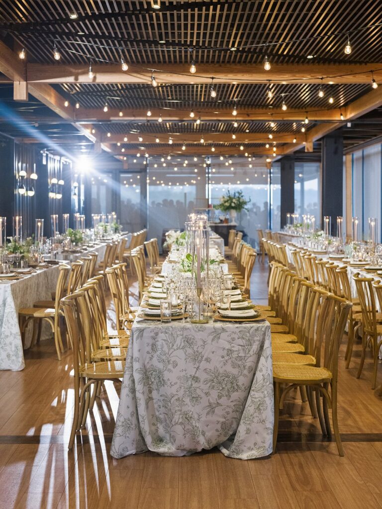 Long candlelit wedding tables beneath the wood ceiling at District Winery