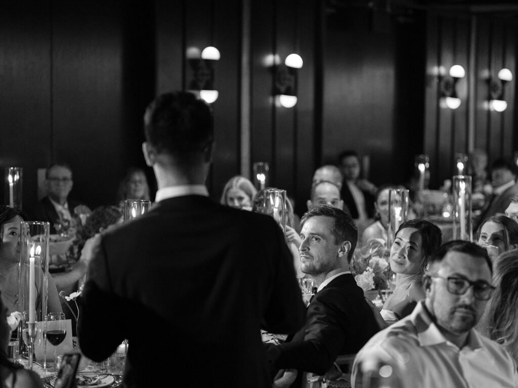 Guests listening to a wedding speech at the candlelit reception