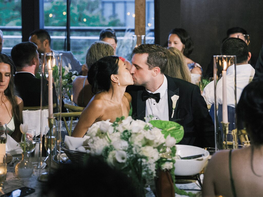Tiffany and Tim kissing at their reception table