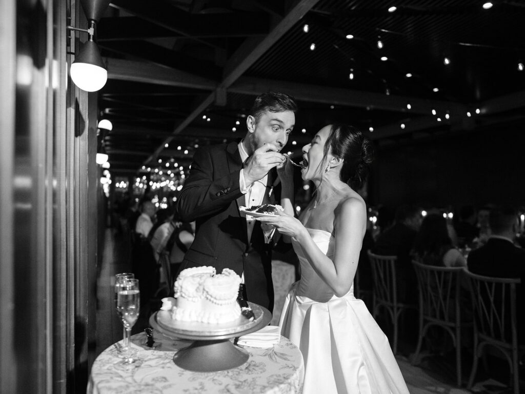Tiffany and Tim cutting their wedding cake in black and white