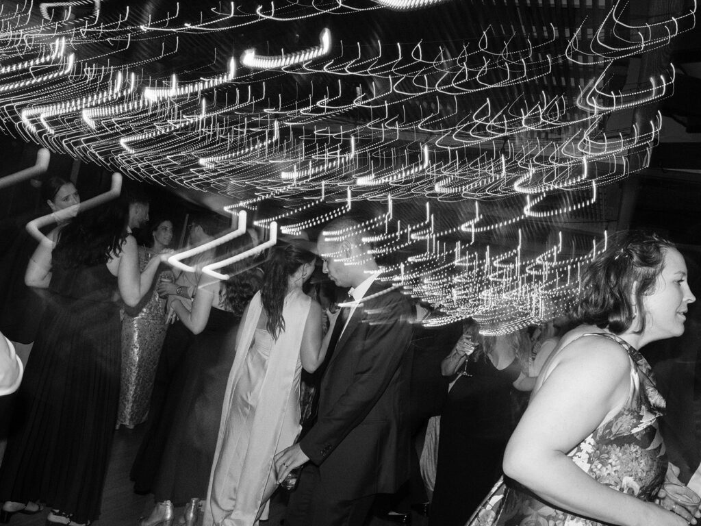 Motion-blurred black-and-white view of wedding guests dancing