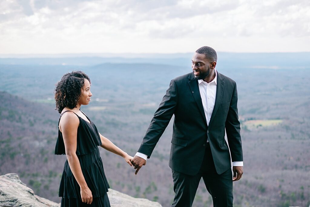 North Carolina wedding photographers: A couple laughing and holding hands while walking on a hiking trail at Hanging Rock State Park.