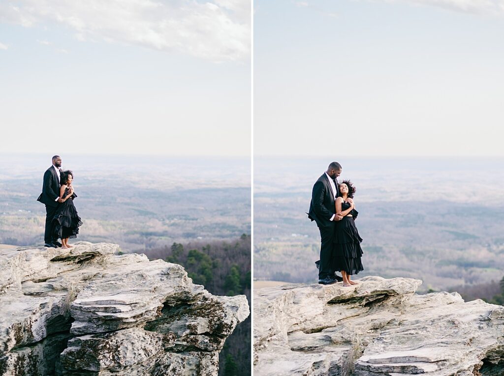 Mountain engagement session: A couple standing on a rocky ledge with Hanging Rock State Park in the background.
