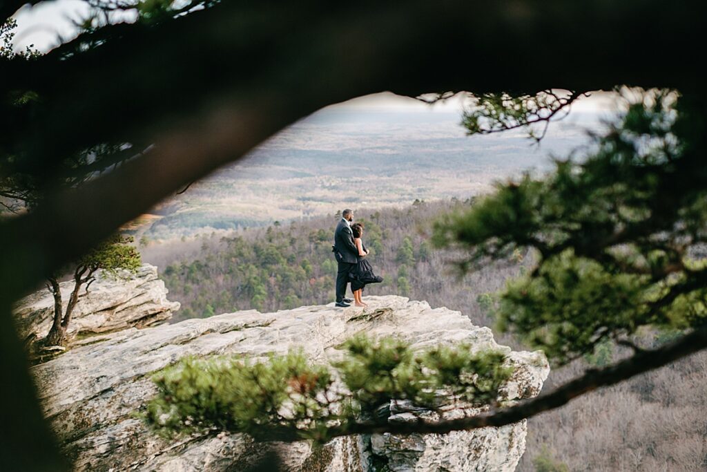 Hanging Rock engagement session: A couple sharing a tender moment while overlooking the stunning mountain views at Hanging Rock State Park.