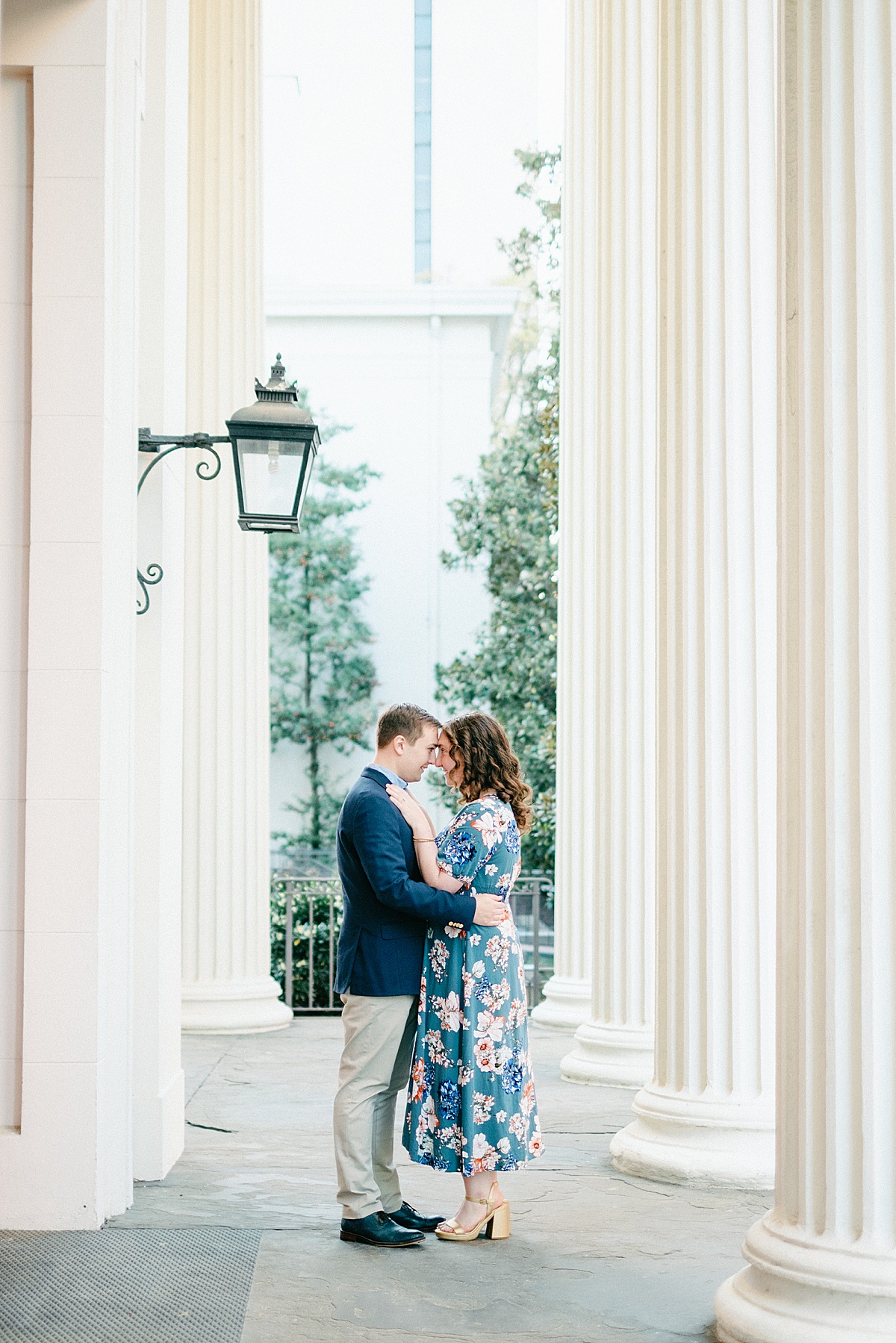 Couple embracing between columns at a Historic building at the Richmond Capitol Building grounds during engagement session